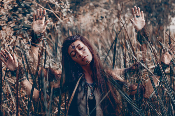 Beautiful young woman model with very long hair on branches. witch craft concept