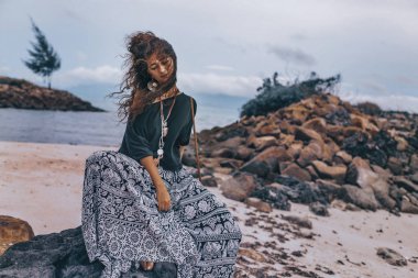 Sahilde oturan güzel genç boho tarzı kadın 