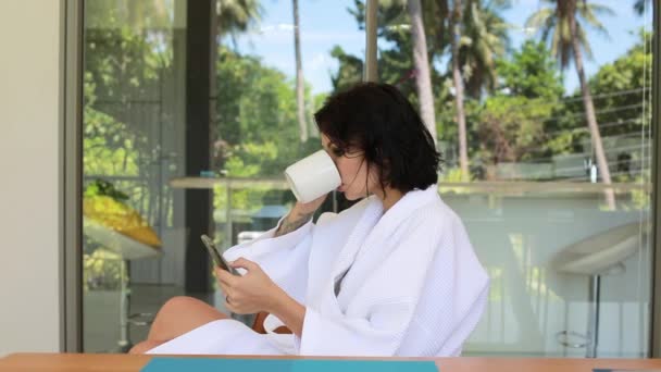 美しい若い女性は ヴィラのテラスでコーヒーを飲むし Selfie を作る 旅行リラックス スパのコンセプト — ストック動画