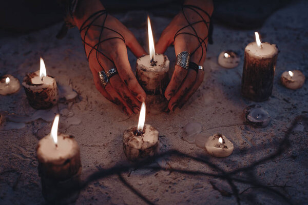 Руки женщины держат свечу близко.
