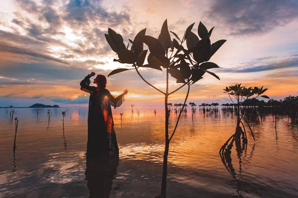 年轻女子站在水面上日落剪影 — 图库照片