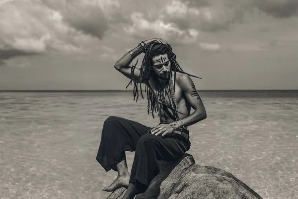 Schöner junger Mann mit traditioneller Körperbemalung am Strand — Stockfoto