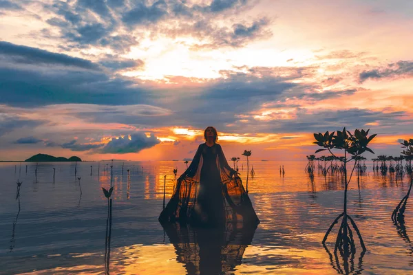 年轻女子站在水面上日落剪影 — 图库照片