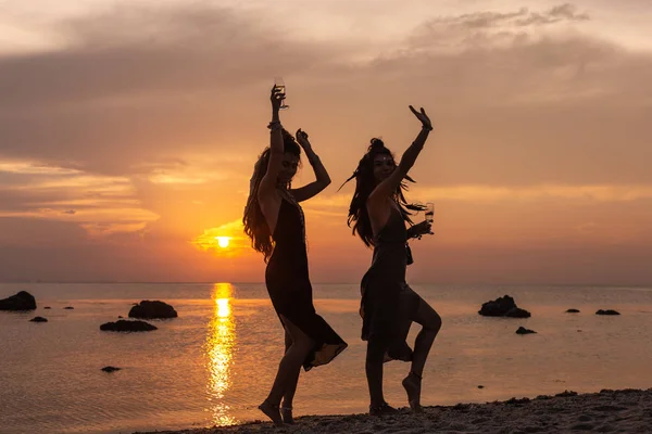 Silueta de dos chicas hermosas jóvenes divirtiéndose en la playa — Foto de Stock
