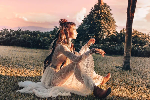 Szép fiatal divatmodell ül egy területen a naplementekor — Stock Fotó