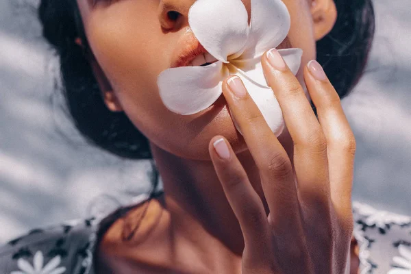 Close up de bela jovem segurando flor de frangipani — Fotografia de Stock