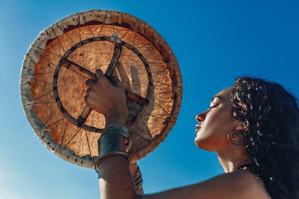 beautiful young woman with shaman drum outdoors 