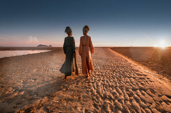 silhouette of two young beautiful girls in turban on the beach 