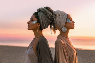 two young beautiful girls in turban on the beach at sunset  clipart