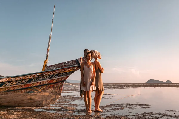 Dos hermosas modelos de moda joven en la playa en barco de mar — Foto de Stock