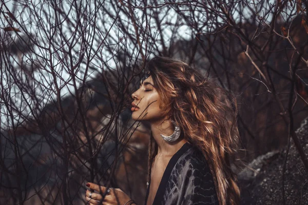 Porträtt av vacker ung kvinna genom torra grenar utomhus — Stockfoto