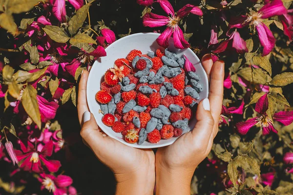 Nahaufnahme von Frauenhänden, die Teller mit frischen Beeren halten — Stockfoto