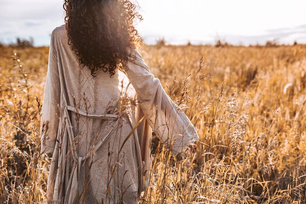 美丽的年轻女子走在日落的田野上 — 图库照片