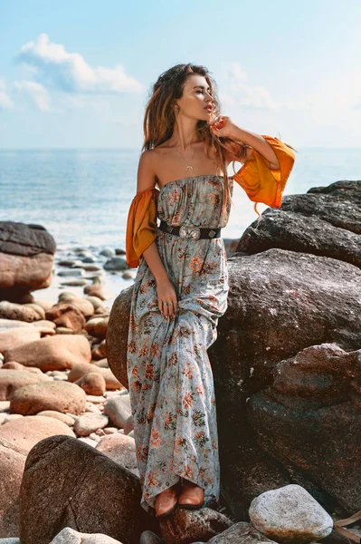 Bella giovane donna alla moda sulla spiaggia di pietra al tramonto — Foto Stock