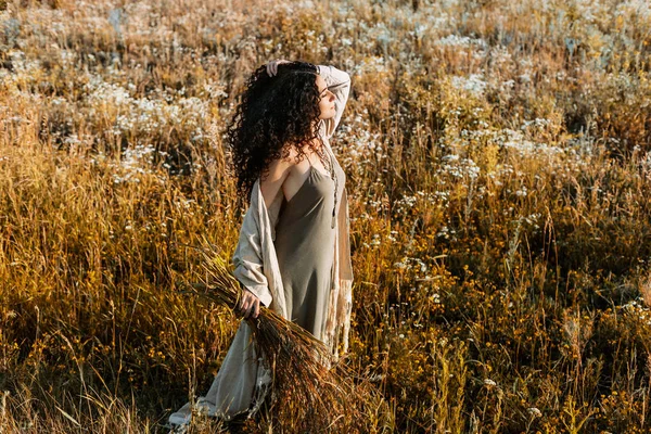 Wanita muda yang cantik berjalan di lapangan saat matahari terbenam — Stok Foto