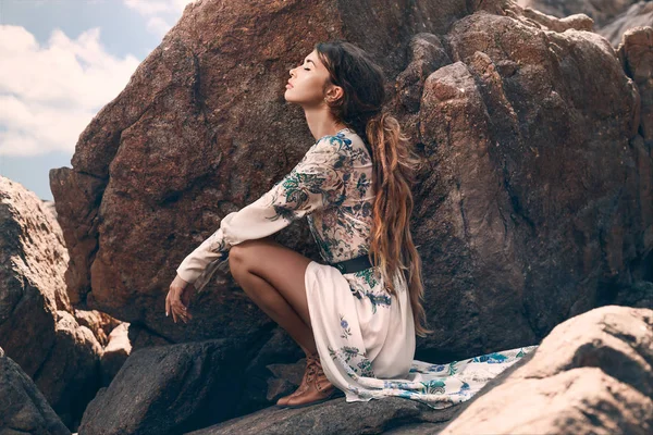 Hermosa joven sentada en la piedra — Foto de Stock