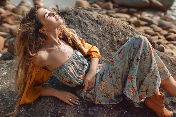 Mujer joven en vestido elegante acostado en la piedra al aire libre — Foto de Stock