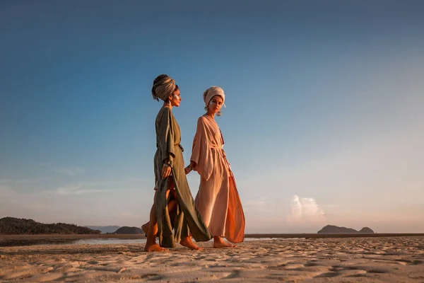 Zwei junge schöne Mädchen im Turban am Strand spazieren — Stockfoto