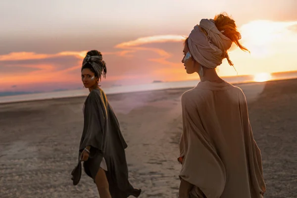 Duas meninas bonitas jovens em turbante andando na praia — Fotografia de Stock