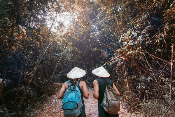 Dos hombres en sombrero vietnamita caminando en el callejón del bosque de bambú — Foto de Stock