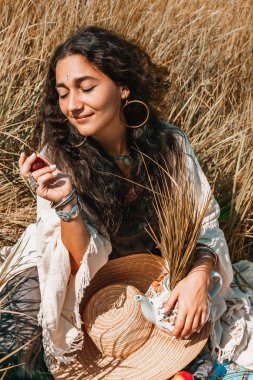 Gün batımında çaydanlıkla birlikte bir tarlada güzel genç bir kadın.