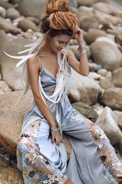 Taş plajda oturan neşeli genç moda kadın — Stok fotoğraf