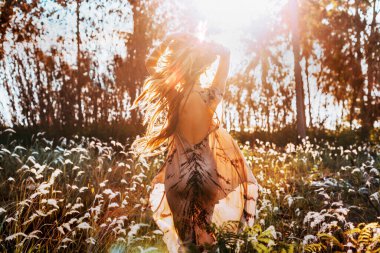  Güzel, genç, şık bir kadın gün batımında sahada eğleniyor.