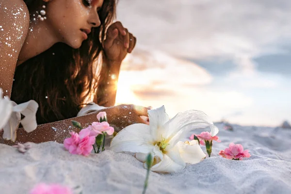 Розовые Лилии Лежащие Песке Переднем Плане Молодая Красивая Женщина Лежащая — стоковое фото