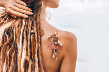 Kumsalda güzel bir genç kadın. Omzunun üstünden. Yakın çekim.