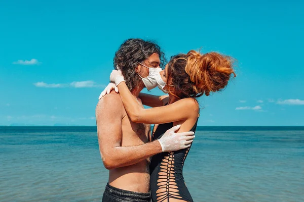 Pareja Joven Abrazándose Besándose Través Las Máscaras Faciales Playa — Foto de Stock