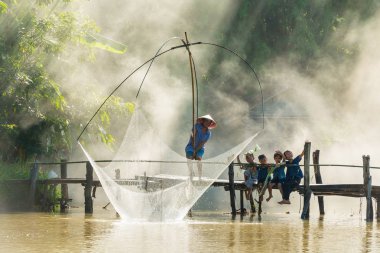 Sakon Nakhon, Tayland - 31 Temmuz 2016: Kırsal adam Balıkçılık Balıkçılık net süre ahşap Köprü'bataklık üzerinde duman arka plan ile birlikte oturan ve muz üzerinde kafa Sakon: Tayland Nakhon yapraklar tutan kırsal çocukların grup
