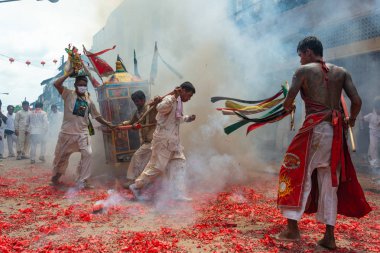 Phang Nga, Tayland - 14 Ekim 2018: Grup tahtırevan içinde sokakta yürüyen insanlar ibadet Tanrı Phang Nga, Tayland vejetaryen Festivali geçit havai fişek ateş ederken Çin Tanrı heykeli ile holding beyaz elbiseli adam