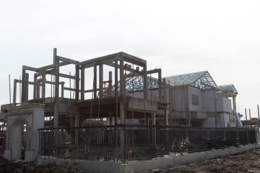 Ev yapım aşamasında bir bina sitesi, göl kenarında beyaz arka plan üzerinde.