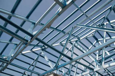 Structure of steel roof frame for building construction isolated on blue sky background. clipart