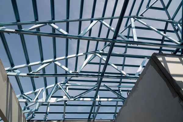 Structure of steel roof frame for building construction isolated on blue sky background.