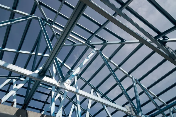Structure of steel roof frame for building construction isolated on blue sky background.