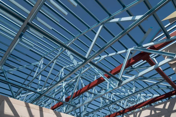 Structure of steel roof frame for building construction isolated on blue sky background.