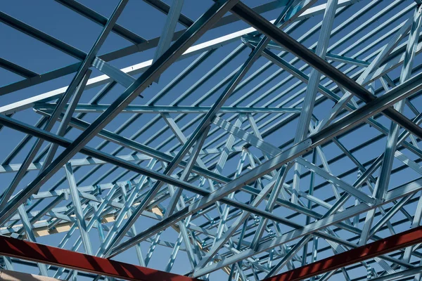 Structure of steel roof frame for building construction isolated on blue sky background.