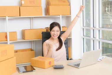 Coşkulu bir kadın, ev tabanlı e-ticaret girişimiyle başarıya ulaşmanın heyecanını gösteriyor..