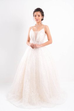 Beyaz gelinlik ve kolyeli güzel Asyalı gelin beyaz arka planda stüdyo çekimlerinde zarif bir poz veriyor..