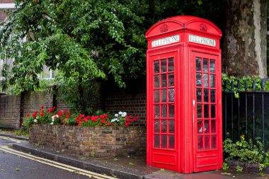 Tipik Londra telefon kulübesi yağmurlu bir gün ve güzel bir bahçe içinde belgili tanımlık geçmiş.
