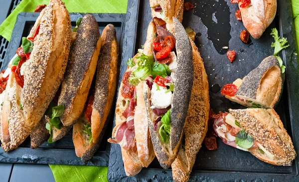 Unique handmade bread sandwiches with ham, mozzarella, dried tomatoes, watercress and gilmil.