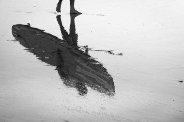 Onun ayağa denizden gelen surfboard ile bir sörfçü yansıması.