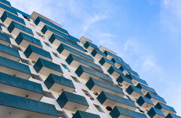 Vintage white building with blue balcony on a blue sky.