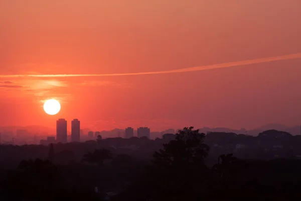 Kondensstreifen, die ein Flugzeug bei Sonnenuntergang in der Stadt São Paulo hinterlassen hat — Stockfoto