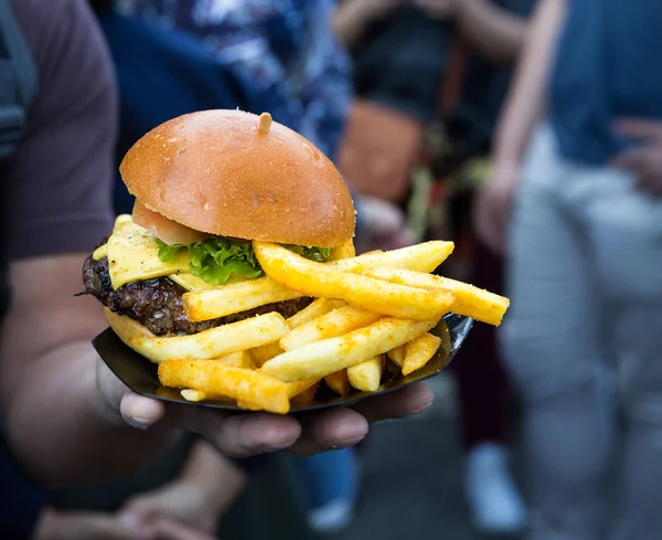 Hombre sosteniendo una ensalada de hamburguesas con papas fritas — Foto de Stock