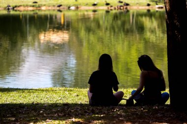 Gölün kenarında oturan iki arkadaş.