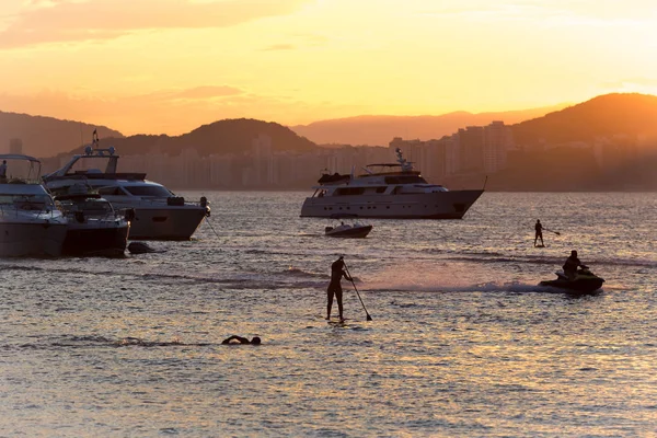 Puesta de sol en la playa de Enseada con gente practicando varios deportes y m — Foto de Stock