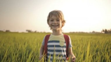 Gülümseyen çocuk okuldan eve pirinç alanının yeşil çim.
