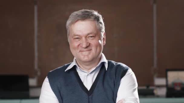 Senior teacher smiling into camera on blackboard background — Stock Video